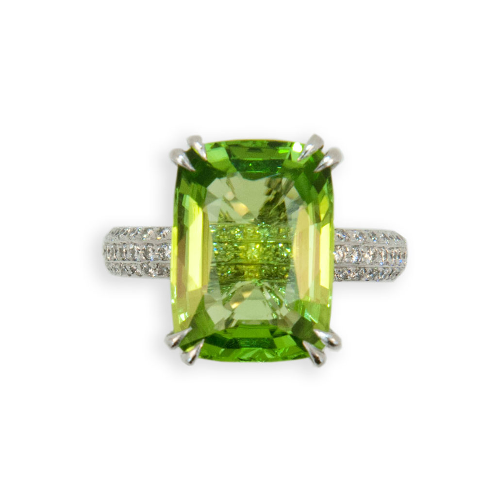 Very fine emerald cut Peridot 8.82cts. Shallow cut stone allows peek through to extravagant diamond shank. Peridot is set in an 18K white gold mounting with split prongs. 153 Round diamonds 1.19cts.twt. Diamonds set on shank all the way around except on sizing bar at bottom. Diamonds are also under bezel beneath peridot. Size 6.5 with sizing horseshoe. One of a kind.