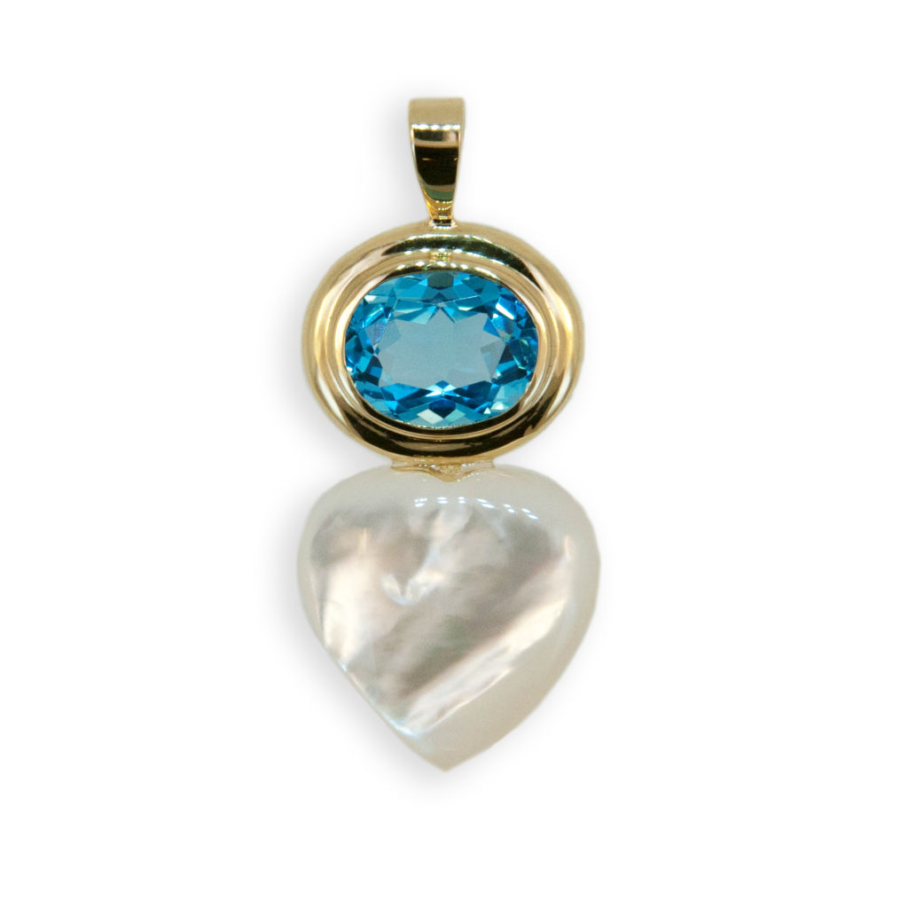 18k yellow gold pendant bezel set with one oval faceted approximately 10x8mm Blue Topaz weighing 3.22cts. and one 15mm heart shaped Mother of Pearl.