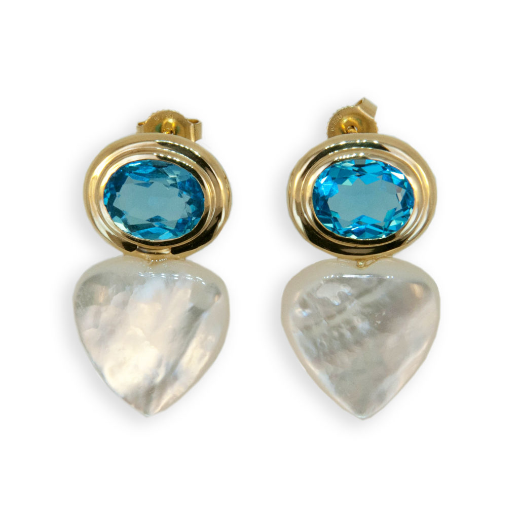 18 karat yellow gold earrings each bezel set with one oval approximate 10x8 millimeter Blue Topaz 6.50 carats total weight. and one 15 millimeter Mother of Pearl heart shape. Friction posts and backs.
