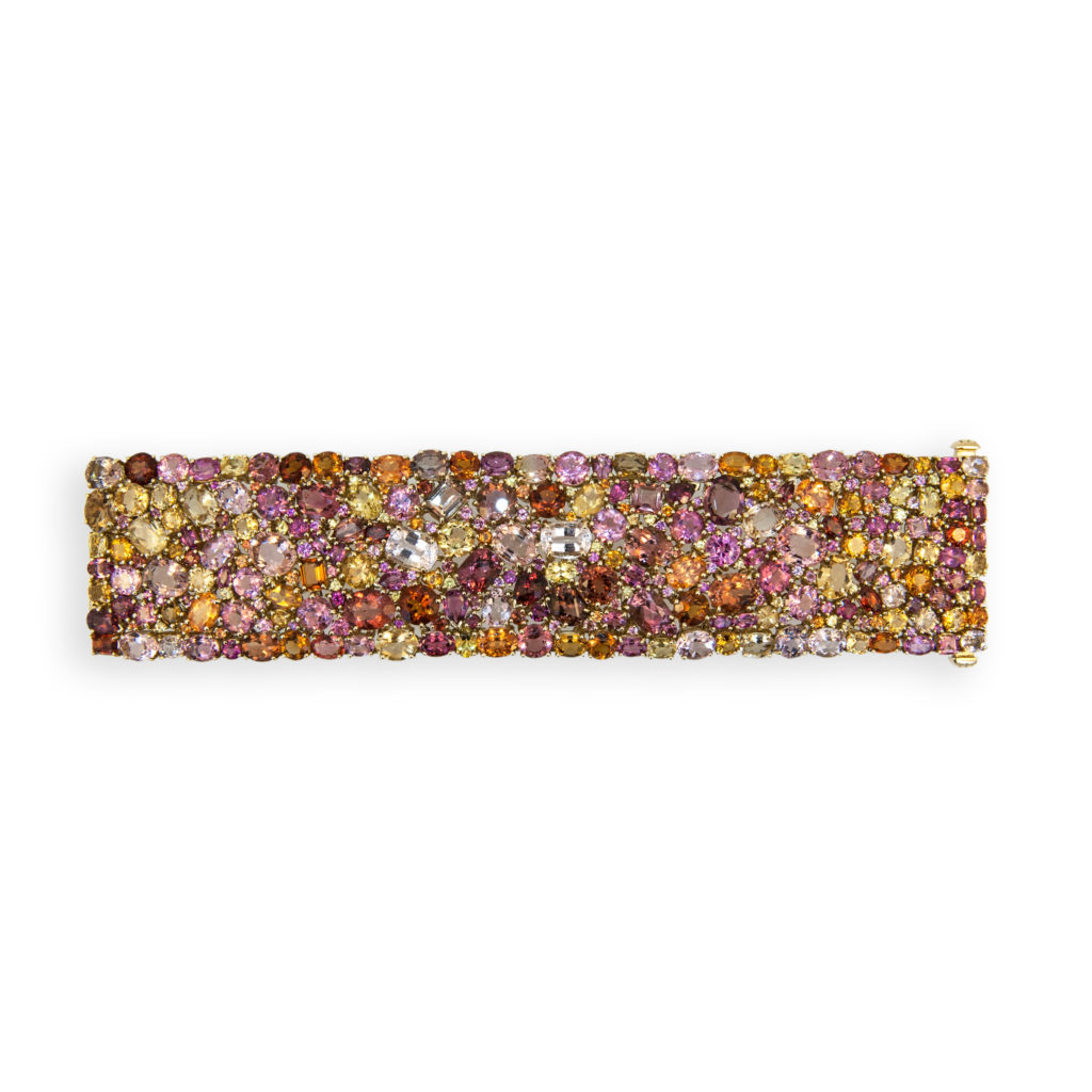 Magnificent 18k yellow gold Kaleidoscope bracelet. Set with 311 multi-colored, multi-shaped Citrine, Mandarin Garnet, Beryl, Garnet,Tourmaline and Sapphire. 173.62cts.twt. Shades of pink, yellow, orange and brown. 1 1/2" wide , 7 inch length. Lavish use of rare "jelly bean" colored mandarin garnets. Each stone meticulously placed by the designer to feel like a kaleidoscope of color. Each stone is set individually allowing the bracelet to be very flexible. One of a kind.