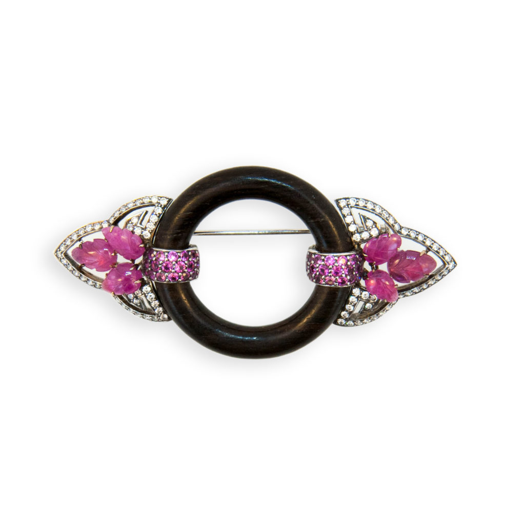 18 karat blackened rose and white gold brooch. Dark wood circle (6) Pink Sapphire leaf cut 6.05 carats total weight (42) round Pink Sapphires 1.25 carats total weight and (90) round Diamonds 1.00 carats total weight