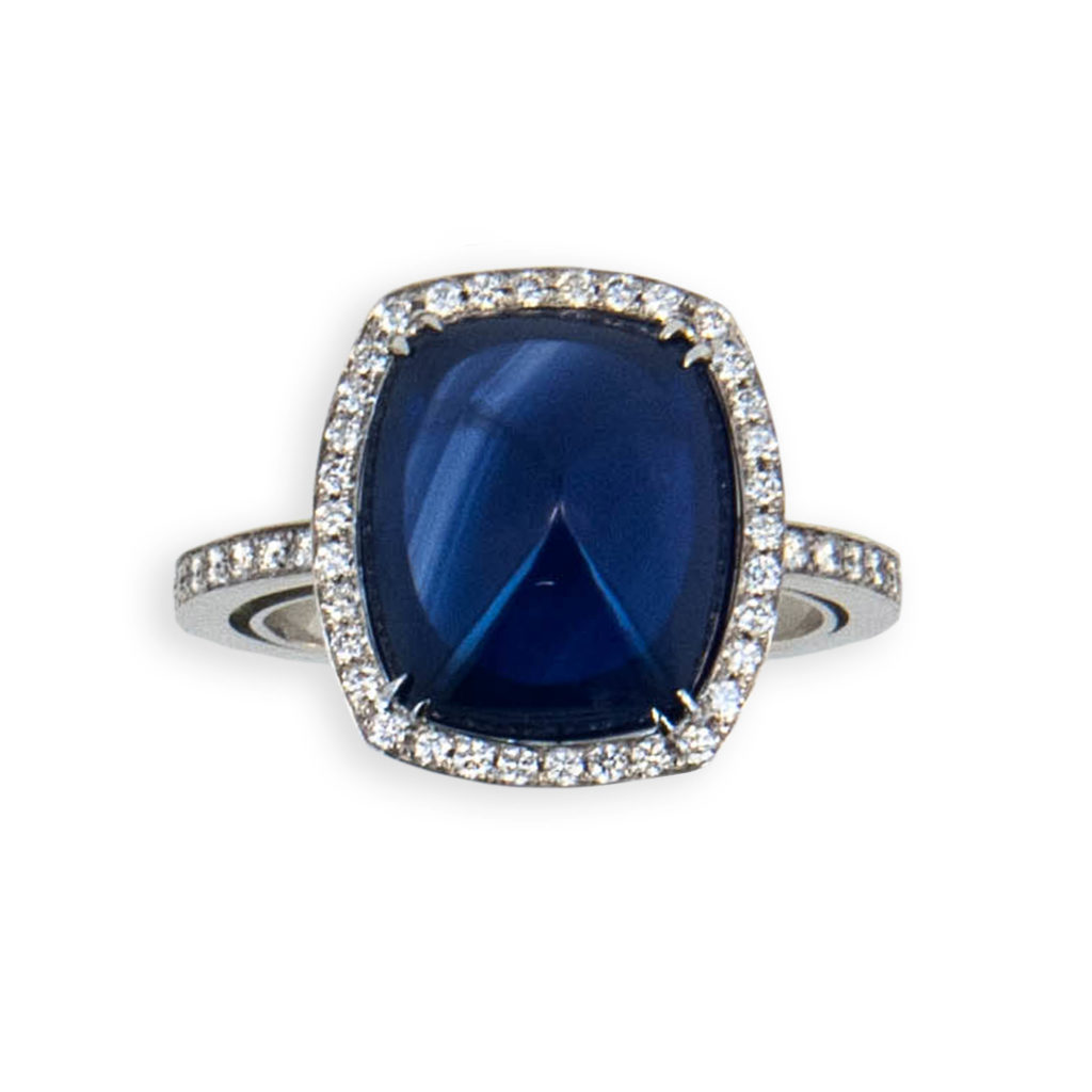 18 karat white gold ring set with (1) 9.02 carat sugarloaf cut Blue sapphire set with (70) microset diamonds .40 carats total weight. Size 6 3/4. With Horseshoe in shank.