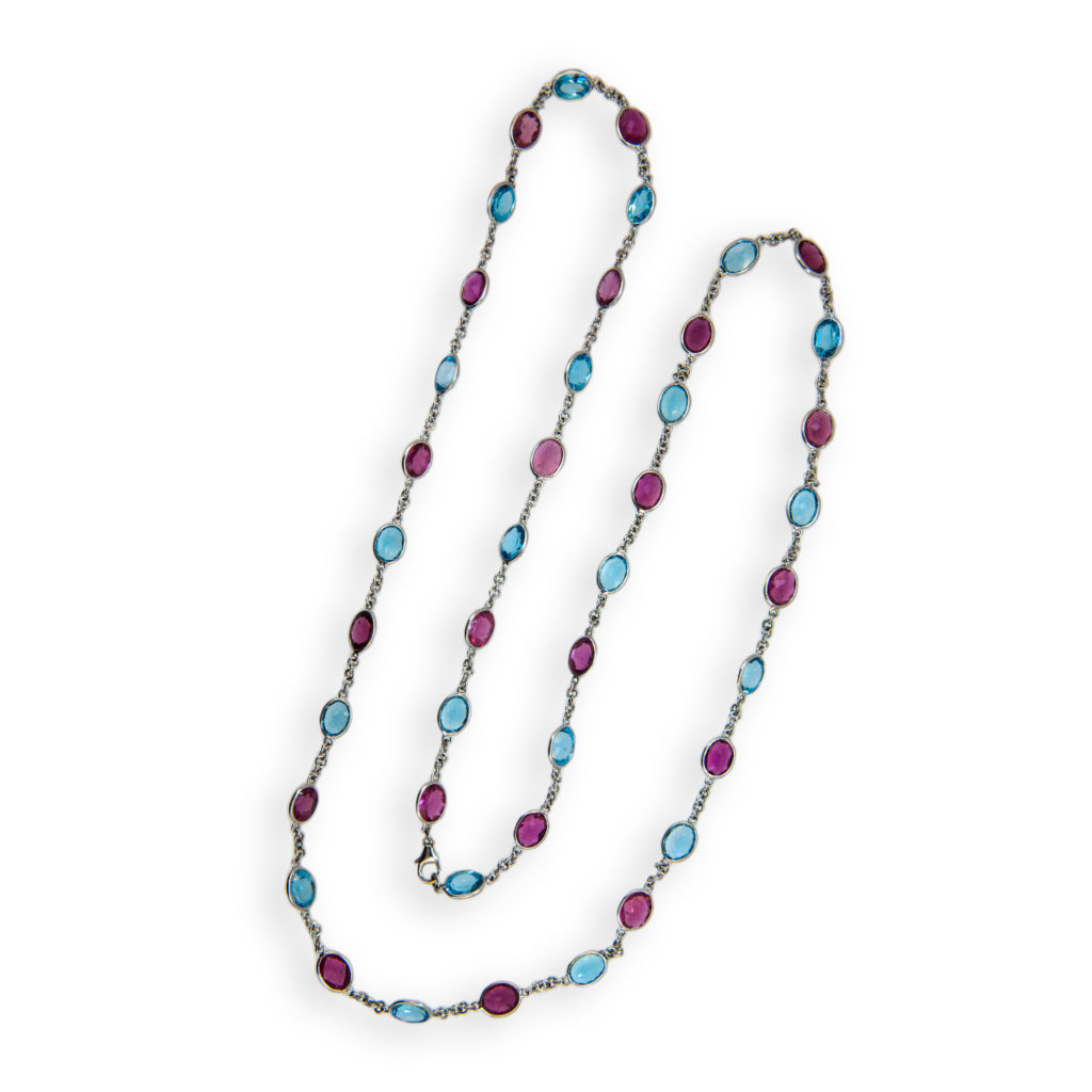 18 karat white gold 31.25 inch chain with oval Pink Tourmaline and Blue Topaz (42) oval 8 x 6 mm stones, 21 Pink Tourmaline approximately 23.52 carats total weight and 21 Blue Topaz approximately 29.61 carats total weight. Lobster style clasp.