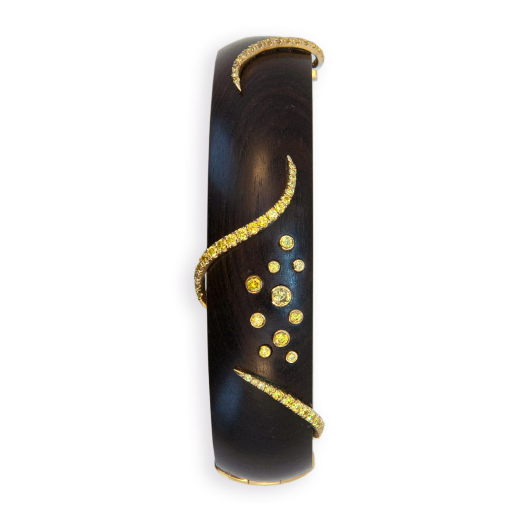18 karat yellow gold on Grenadill wood bangle 5/8 inches wide three swirl designs are set with (52) round yellow diamonds and (10) various size yellow diamonds are tube set, total weight of (62) yellow diamonds is .97 carat total weight