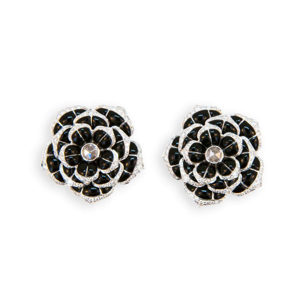 18 karat white gold flower style earrings set with 35 pieces of onyx in each earring 70 total. Edges of petals are set with 150 round diamonds 1.05 carats total weight and center of each flower is set with one rose cut diamond two equal .51 carats total weight. Earrings may be worn as clip on or pierced (fold down posts).