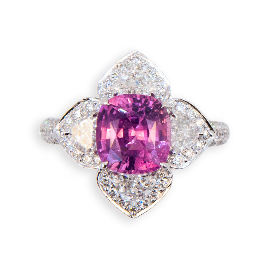 18 karat white gold ring set with one faceted cushion cut Pink Sapphire 3.35 carats. Four fancy shield shaped Diamonds .89 carat total weight and 194 round Diamonds 1.52 carats total weight. Size 6.75 with a horseshoe.