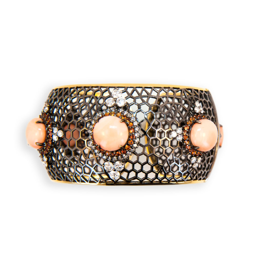 18 karat yellow gold blackened hinged cuff bracelet open web design with five 12.2-12.5 mm round Angel Skin Coral Cabs 40.24 carats total weight. Surrounding each coral cab are Orange Sapphires 110 total 3.67 carats total weight. 83 full-cut diamonds 4.51 carats total weight.