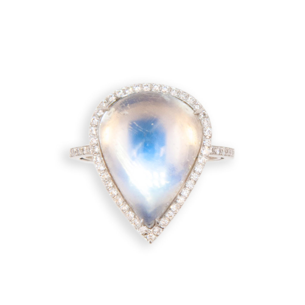 18 karat white gold ring set with one pear shape cabochon Moonstone 8.08 carats surrounded by 43 diamonds, shank is set with 36 diamonds. (79) total .33 carat total weight. Ring is a size 6.25 with a horseshoe.