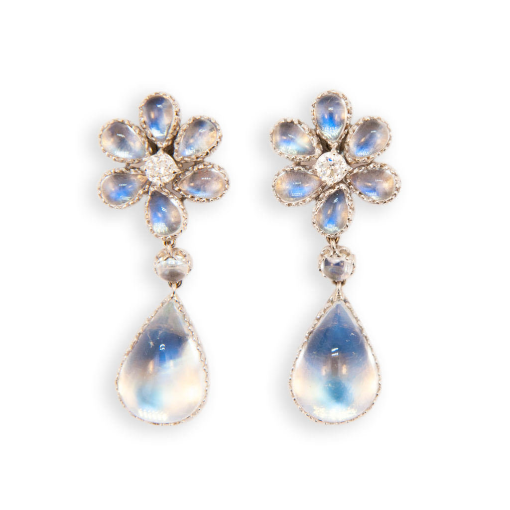 18 karat white gold drop earrings flower style top each set with (6) pear shaped cabochons 6 x 4 mm (12) weigh 5.10 carats total weight and one mine cut Diamond 3.6/3.8 mm (2) weigh .52 carat total weight set at bottom is one pear shaped cabochon Moonstone 16 x 11 mm (2) weigh 15.72 carats total weight and set between top and bottom is one round cabochon Moonstone 4 mm (2) weigh .62 carat total weight.