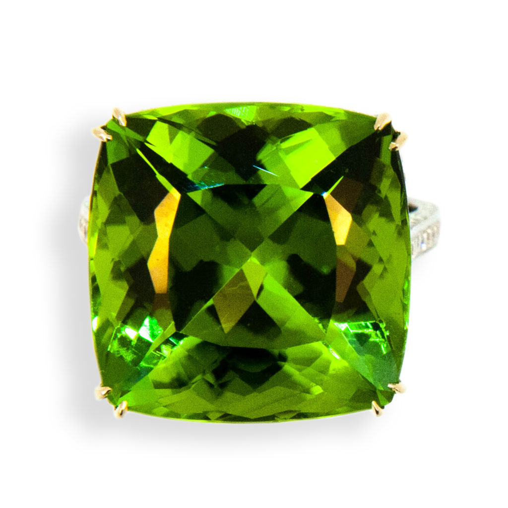 18 karat white gold ring , set with 26.78 carats square faceted cushion cut Peridot. Mounting is set with 226 round diamonds .9-1.4 mm, 1.05 carats total weight. Diamonds are set on under bezel and all sides of shank. Tapered split prongs. Ring is a size 6.75 with a horseshoe.